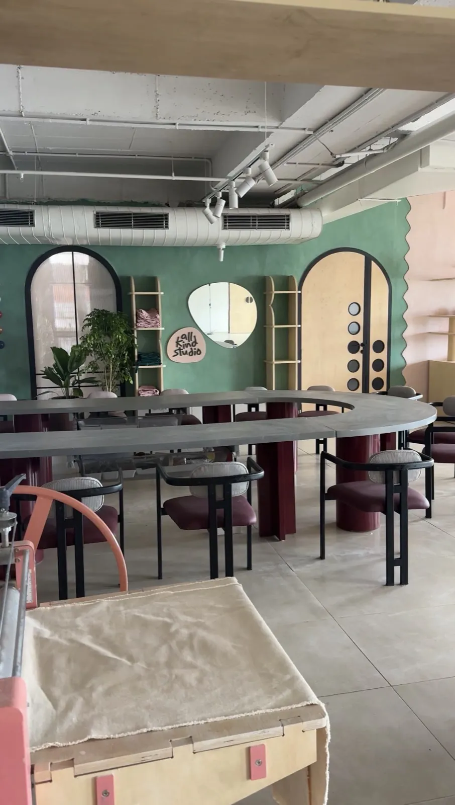 The long table and green wall, with the studio's mirror and arched doors behind